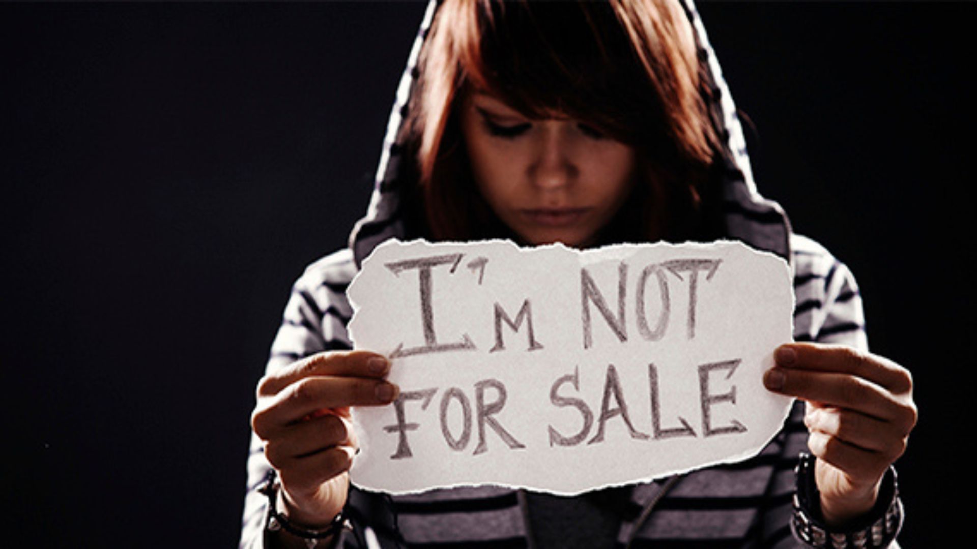 a young girl holding a paper written l'm not for sale showing the fight against forced labour
